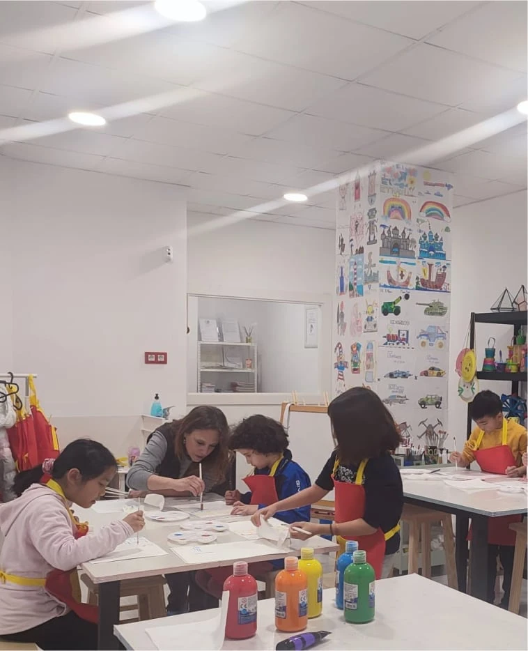 Children And A Teacher Engage In A Painting Class At A Bright Art Studio. Vibrant Colors And Playful Murals Create An Atmosphere Of Creativity And Joy.